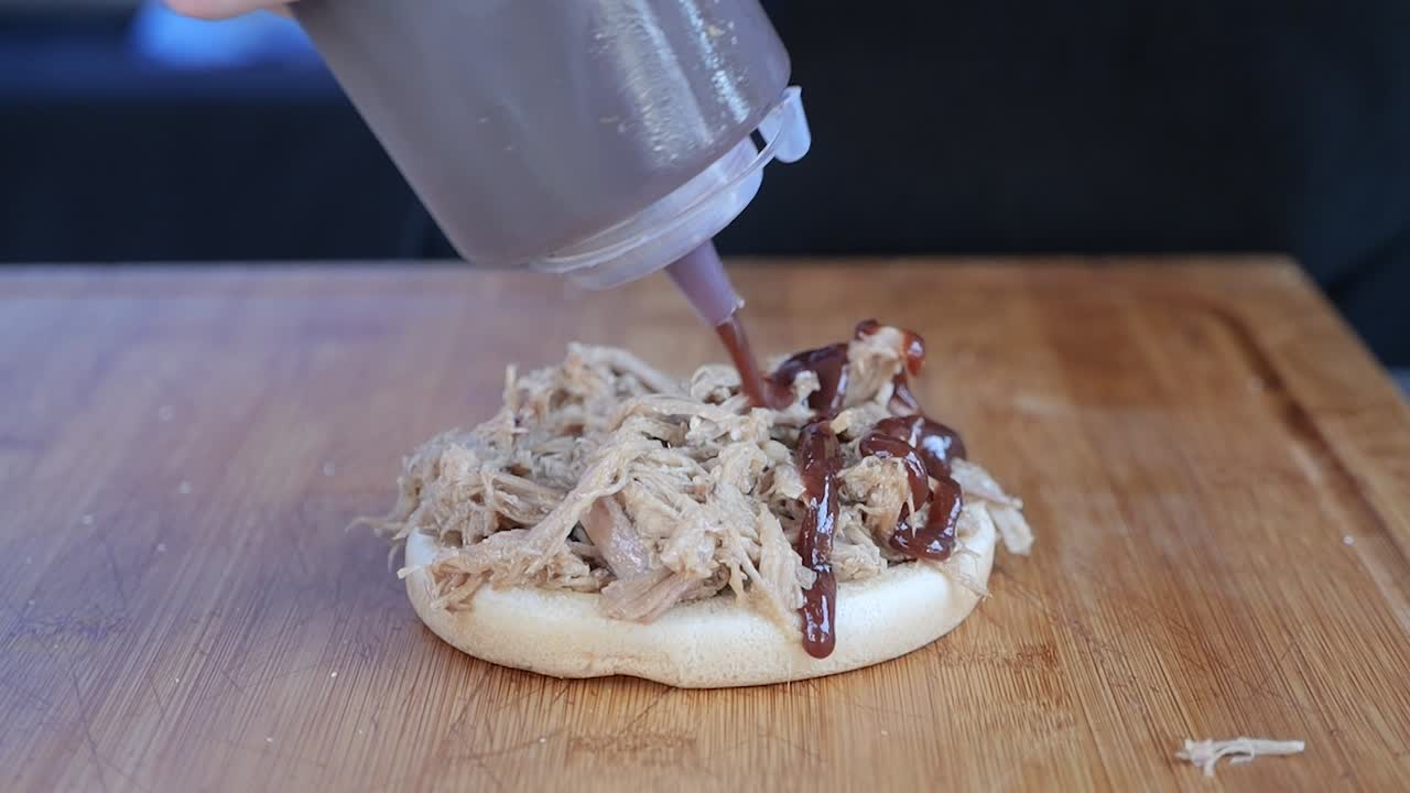 sándwich de puerco desmenuzado rociado con salsa barbacoa a cámara lenta
