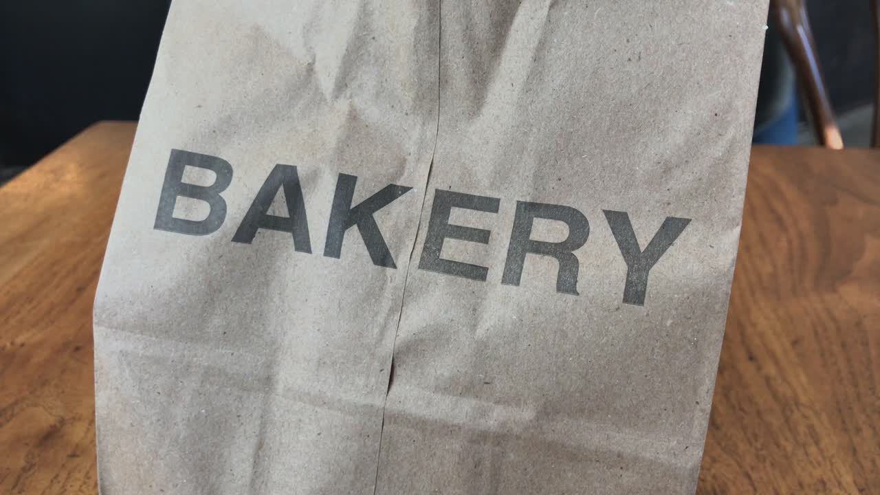 Camera tracking right to left on paper bag with the word bakery printed on it