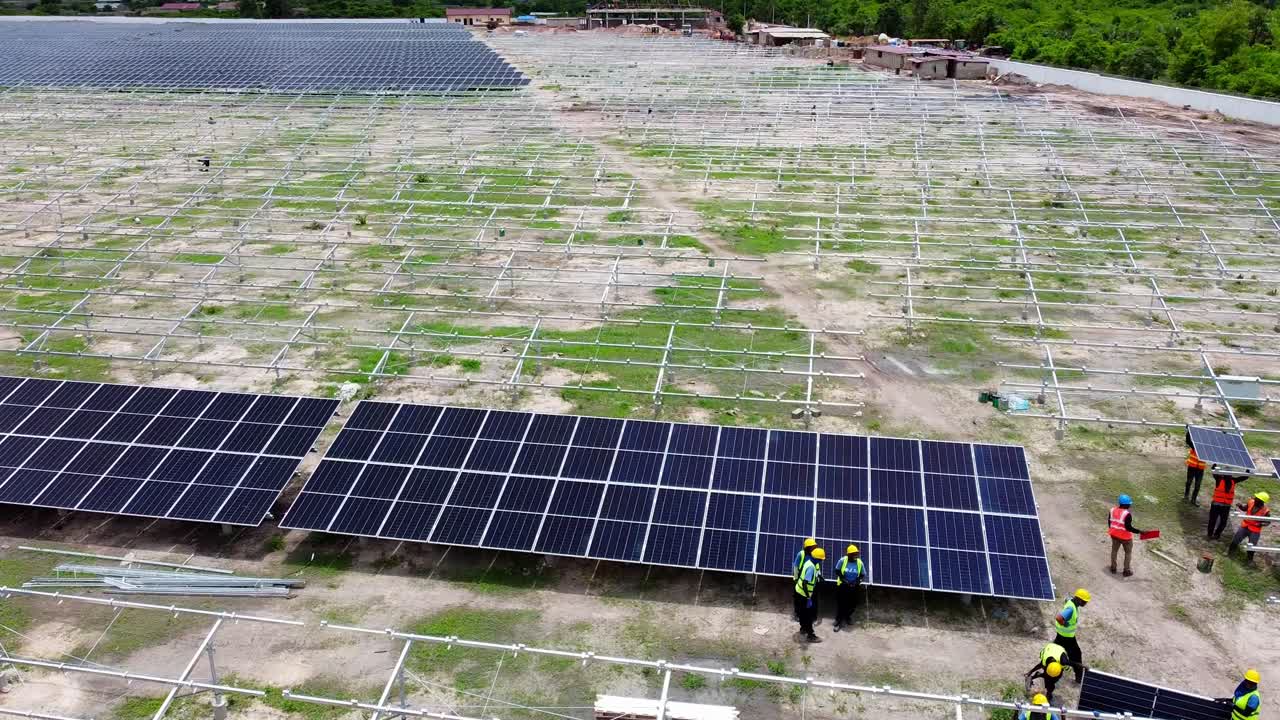 Workers installing solar panels in a large solar farm