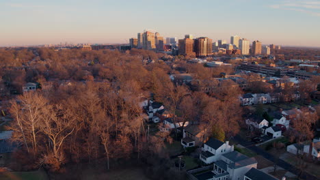 aerial fly away from clayton city skyline and over houses at sunset