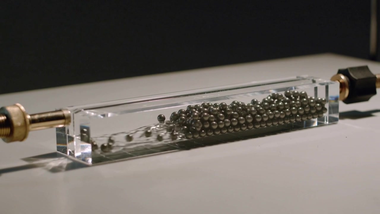 Pulses causing balls rearranging and traveling in acrylic channel on lab bench, connectors staying