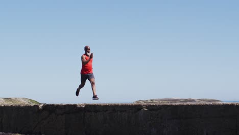 Senior african american man exercising running on rocks by the sea