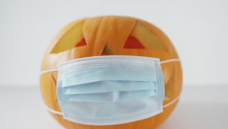 Composition-of-halloween-orange-pumpkin-with-face-mask-against-white-background