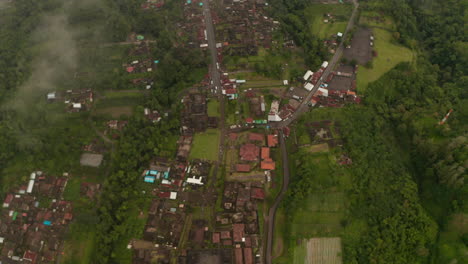 Flying-through-the-clouds-above-Besakih-Temple-in-Bali,-Indonesia.-Top-down-overhead-aerial-view-of-Besakih-Temple-surrounded-by-small-village-full-of-traditional-Bali-houses