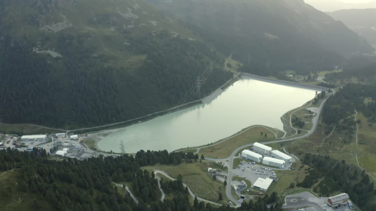 Drone push-in across the Speichersee reservoir dam surrounded by alpine peaks. Great for nature, tourism, and sustainable infrastructure footage