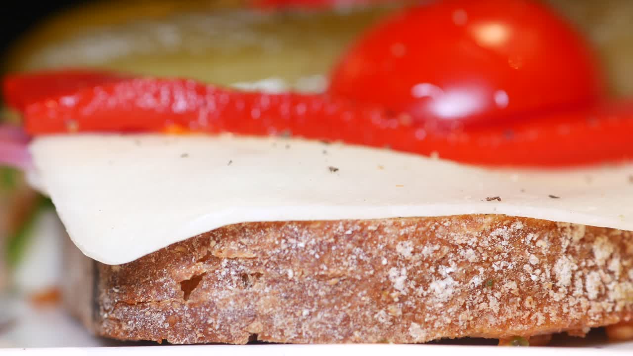 Close-up of a sandwich with cheese, tomato, and peppers