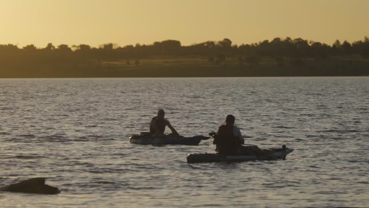 dos hombres remando al hermoso atardecer, aguas tranquilas, vibraciones de verano, actividad saludable