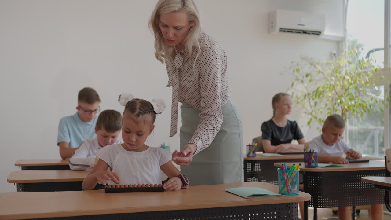 los niños de la clase están sentados en sus escritorios y el maestro camina por la clase y explica el tema de la lección. niños inteligentes aprendiendo en un entorno moderno amigable