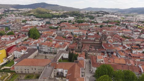 aerial drone footage descending over braga city center, featuring the iconic braga cathedral (sé de braga) and surrounding urban landscape. ideal for travel, tourism, and cityscape projects.
