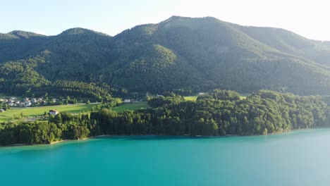 Wunderschöne-Luftaufnahme-Des-Leuchtend-Blauen-Seewassers-Und-Des-Bergwaldes,-Österreich