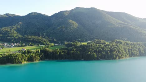 wonderful aerial shot of vibrant blue lake water and mountain forest, austria