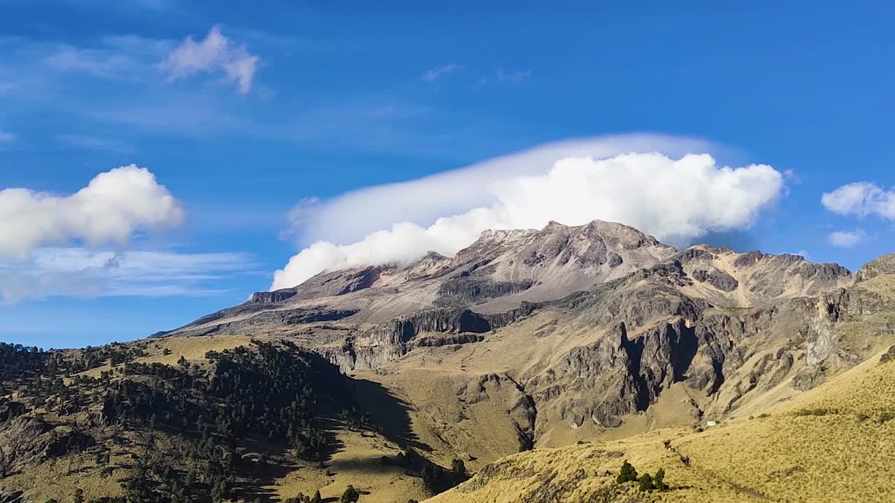 View of Iztaccihuatl mountain in Mexico with clouds rolling over the peaks