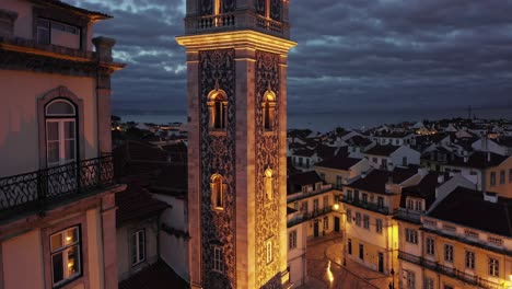 the illuminated lisbon tower stands tall against a dramatic, cloud filled night sky, showcasing its intricate tilework and offering a captivating view of the cityscape below