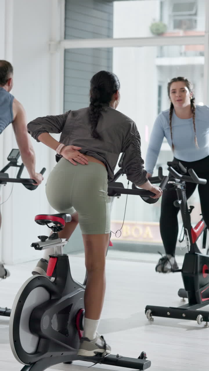 Personas pedaleando en bicicletas estáticas en una clase de gimnasio moderna