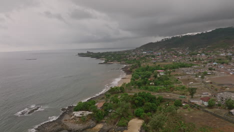 aerial footage of the east coast of sierra leone with dark storm clouds over the mountains in the background