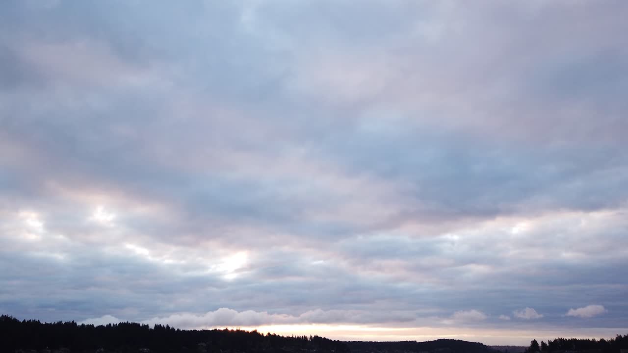 Slow moving hyperlapse clouds crisscrossing over dark land and water. pan left
