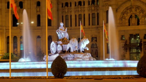 beautifully illuminated cibeles queen fountain in madrid, with water jets and statues, set against a backdrop of historic architecture, creating an elegant and serene nighttime scene