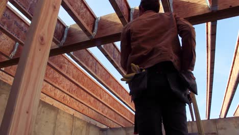 man climbs up a ladder and begins to hammer a nail