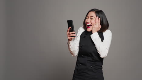 Asian-server-feeling-happy-after-reading-good-news-on-phone