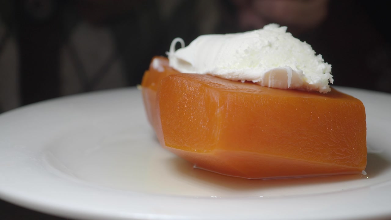 Person Cutting Traditional Candied Pumpkin Dessert with Kaymak