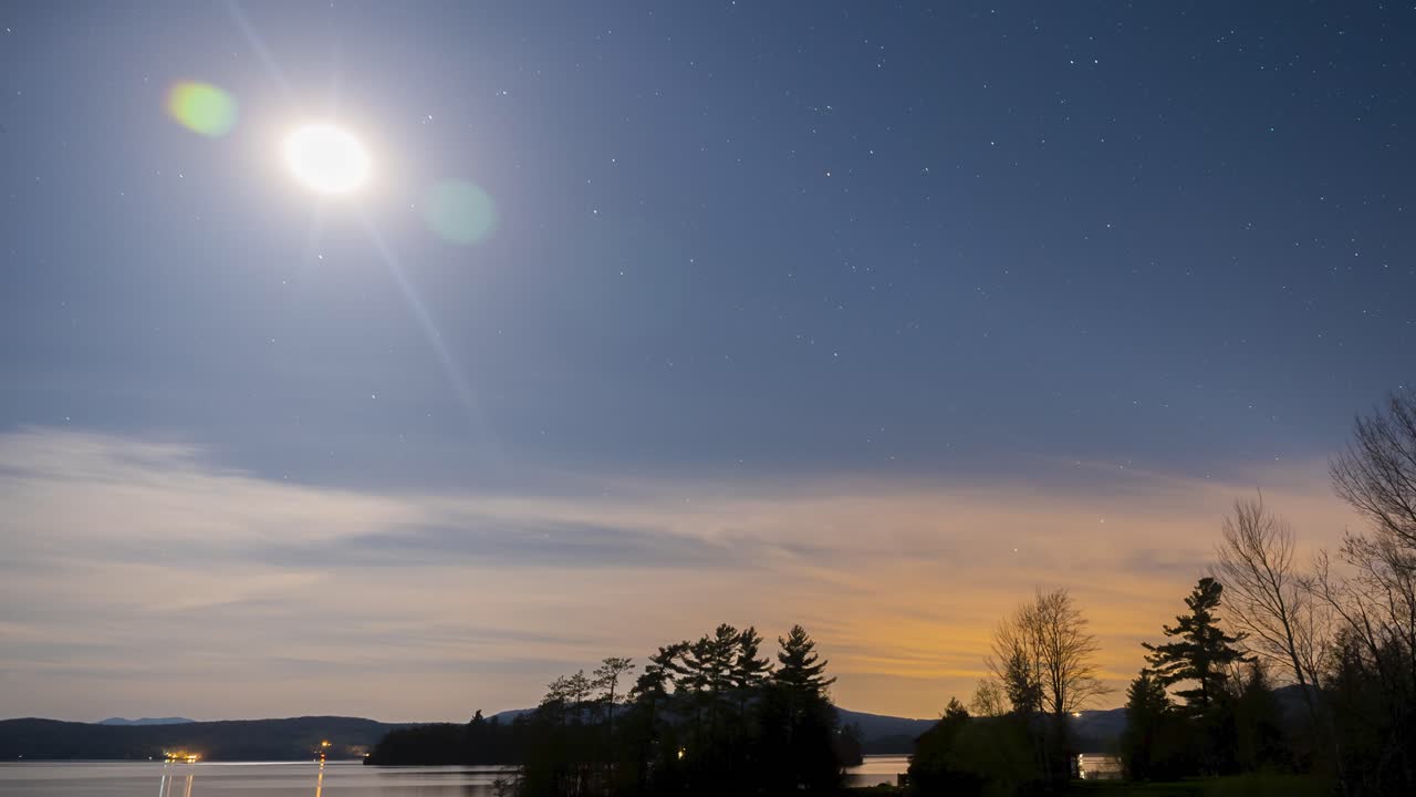 Amazing time lapse of stars moving through the sky over a mountain town lake 4k 30p