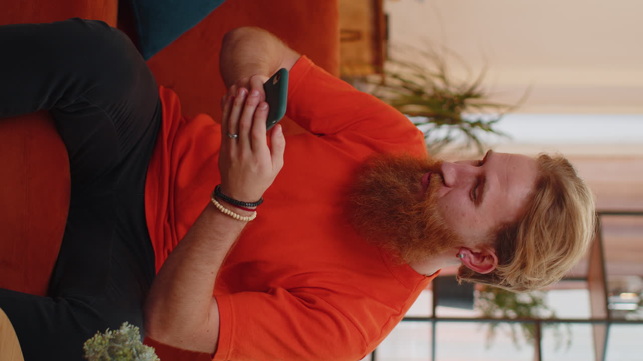 joven guapo en casa usar teléfono inteligente escribir navegación, wow sí descubrió gran gran victoria celebrar