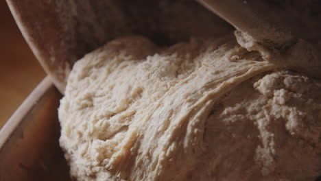 horneado - cuchara de madera moviendo masa de pan de masa fermentada, cámara lenta inclinada hacia abajo