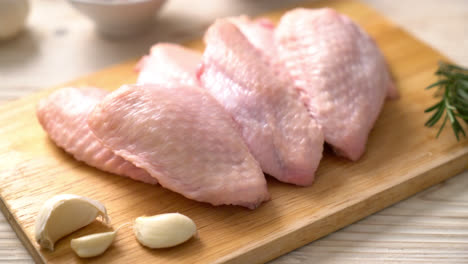 fresh raw middle chicken wings on wooden board with ingredients