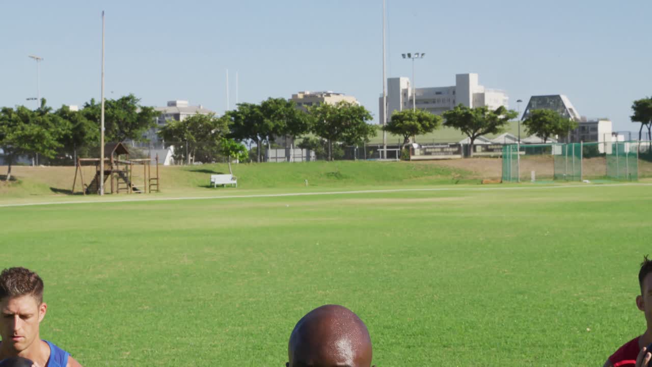 3명의 건강한 남성들로 구성된 다양한 그룹이 야외에서 운동을 하고, 앉아서 케틀벨 무게를 들어 올리고 있습니다.
