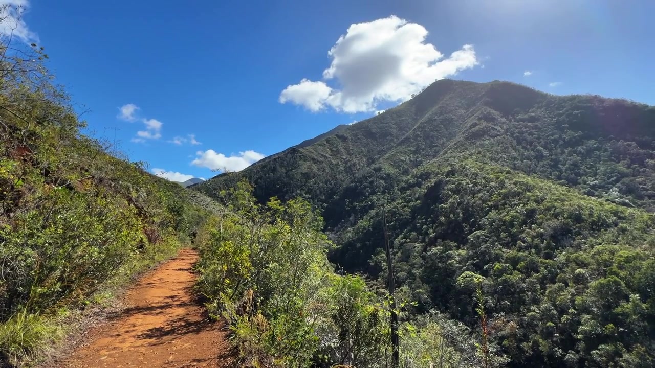 Vista panoramica sulle montagne nell'entroterra con una strada sterrata rossa in una giornata di sole con cieli azzurri