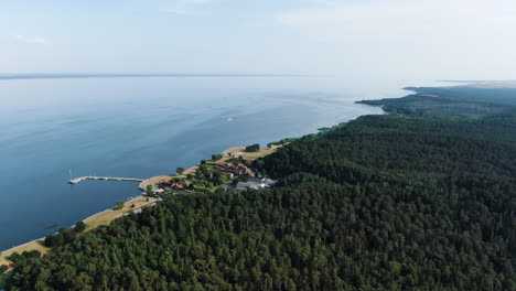 juodkrante town with small pier surrounded by dense forest and curonian lagoon, aerial drone view