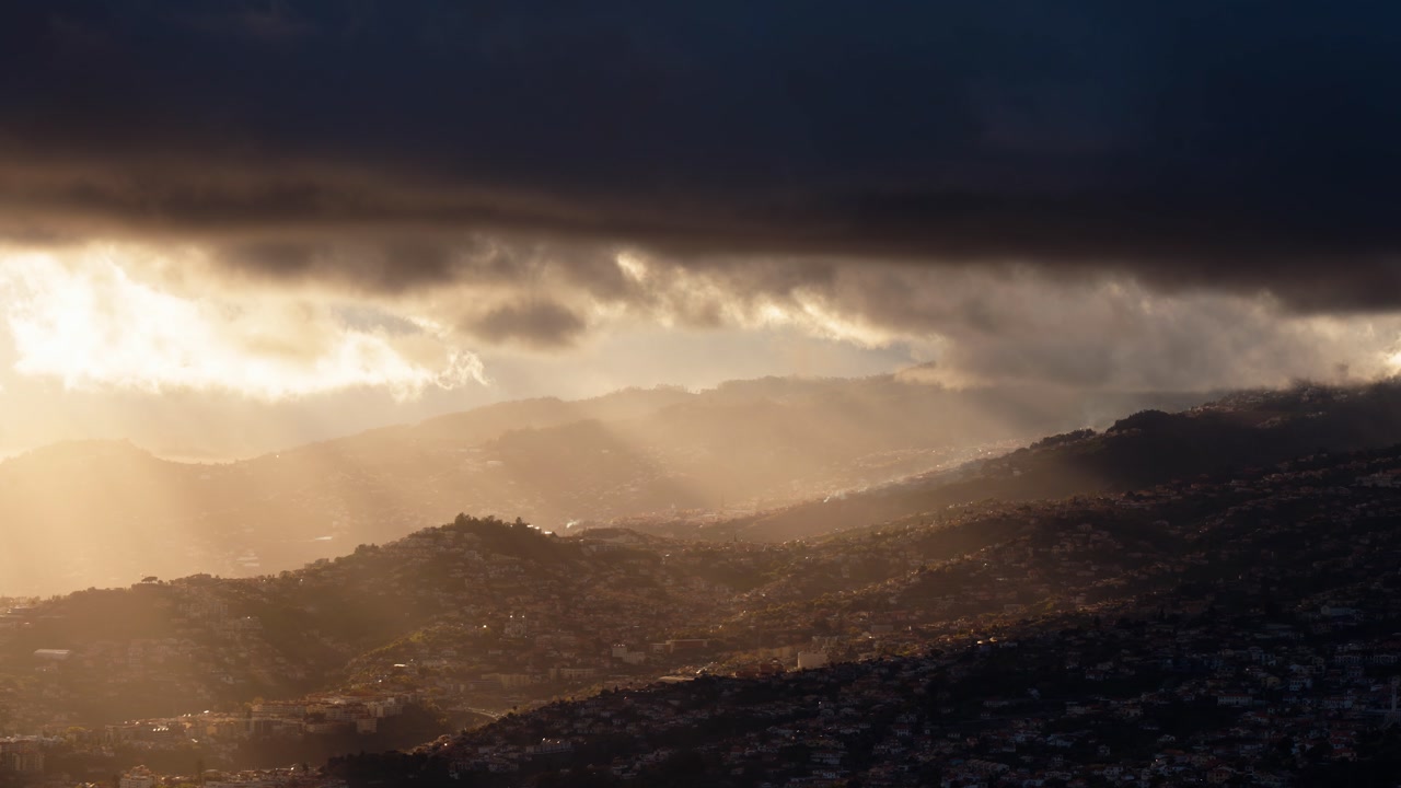 Timelapse of sunlight breaking through clouds over mountain landscape in Madeira