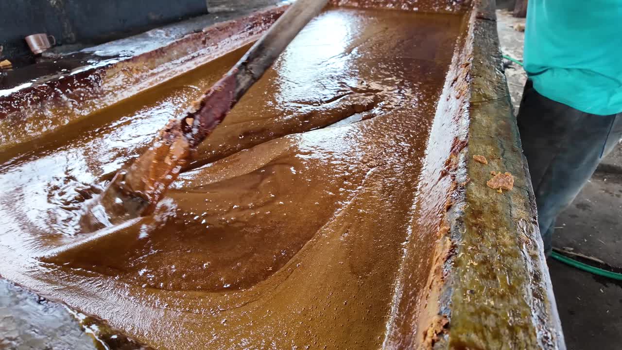 Making panela in a traditional sugar mill, showing unrefined sugar flowing through the process