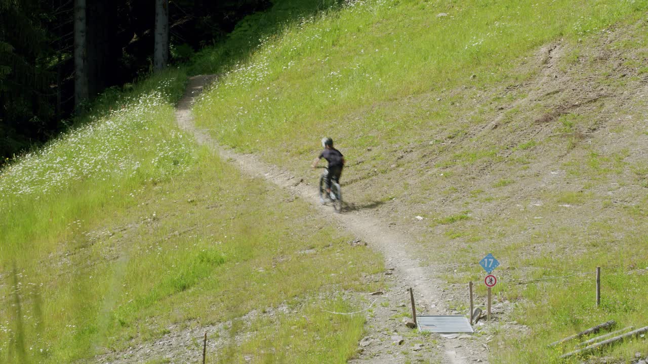 un ciclista de montaña recorre un sendero azul a través de un campo de hierba.