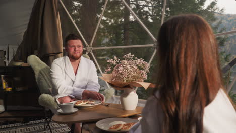 couple enjoying breakfast in a glamping dome tent