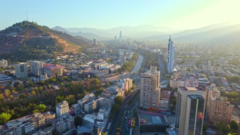 Sunset-casting-a-warm-glow-over-the-Santiago-skyline,-showcasing-urban-bustle-and-cityscape-beauty,-aerial-view