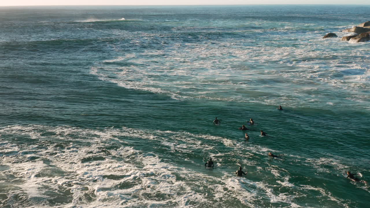 antena de surfistas sentados en sus tablas de surf y esperando la próxima ola en llandudno, ciudad del cabo