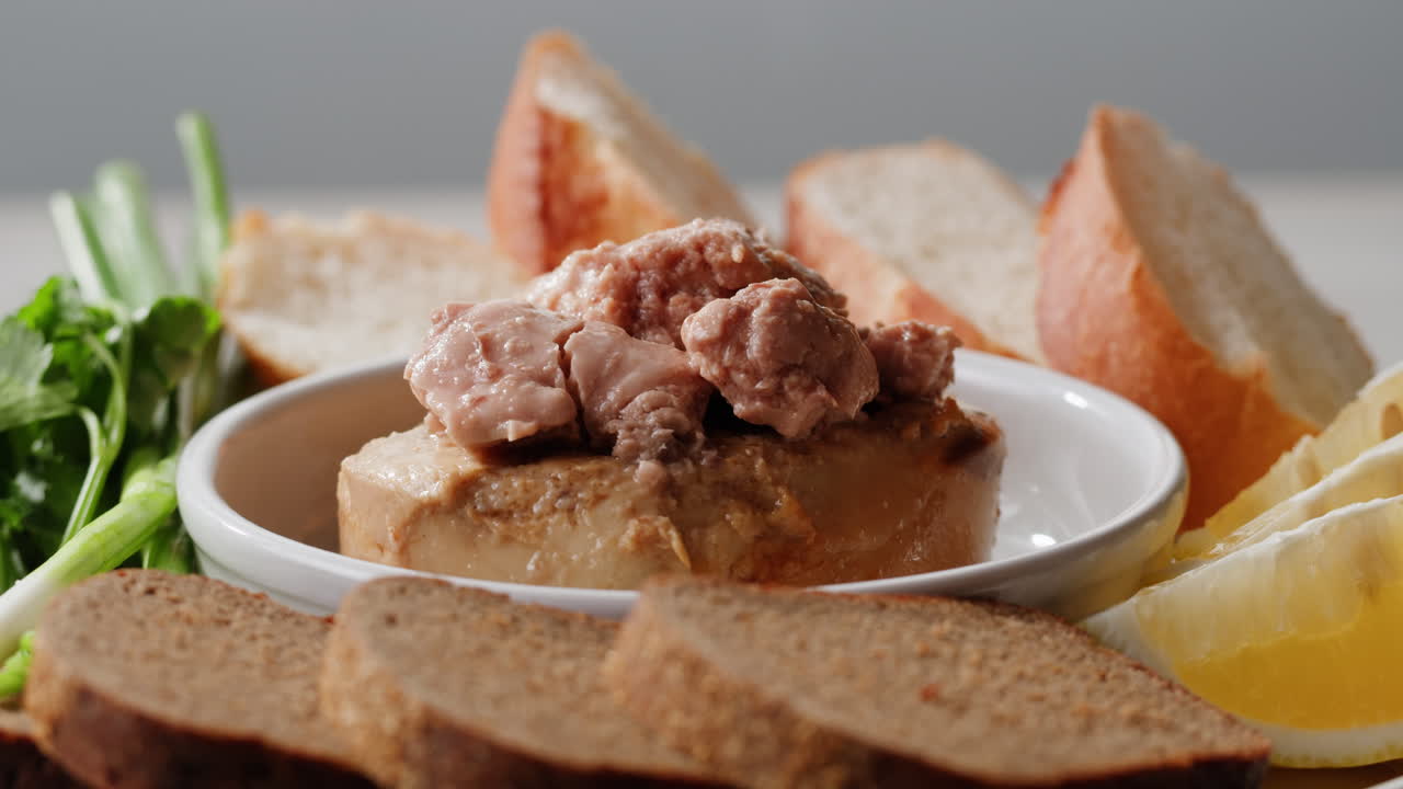 Smoked cod liver in oil in open tin can with fresh greens on wooden table. Seafoods delicacy. High quality 4k footage