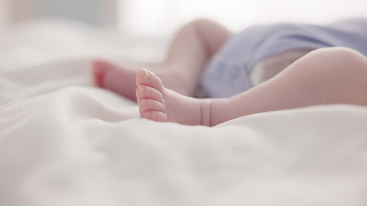 Sleeping, dreaming and feet of baby on bed