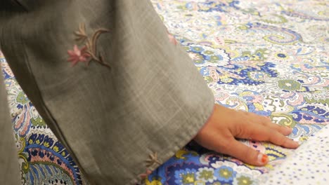 woman's hand touching a floral patterned fabric