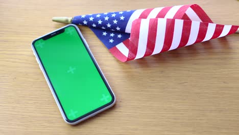 american flag lying on the table with mobile phone chroma key mockup screen