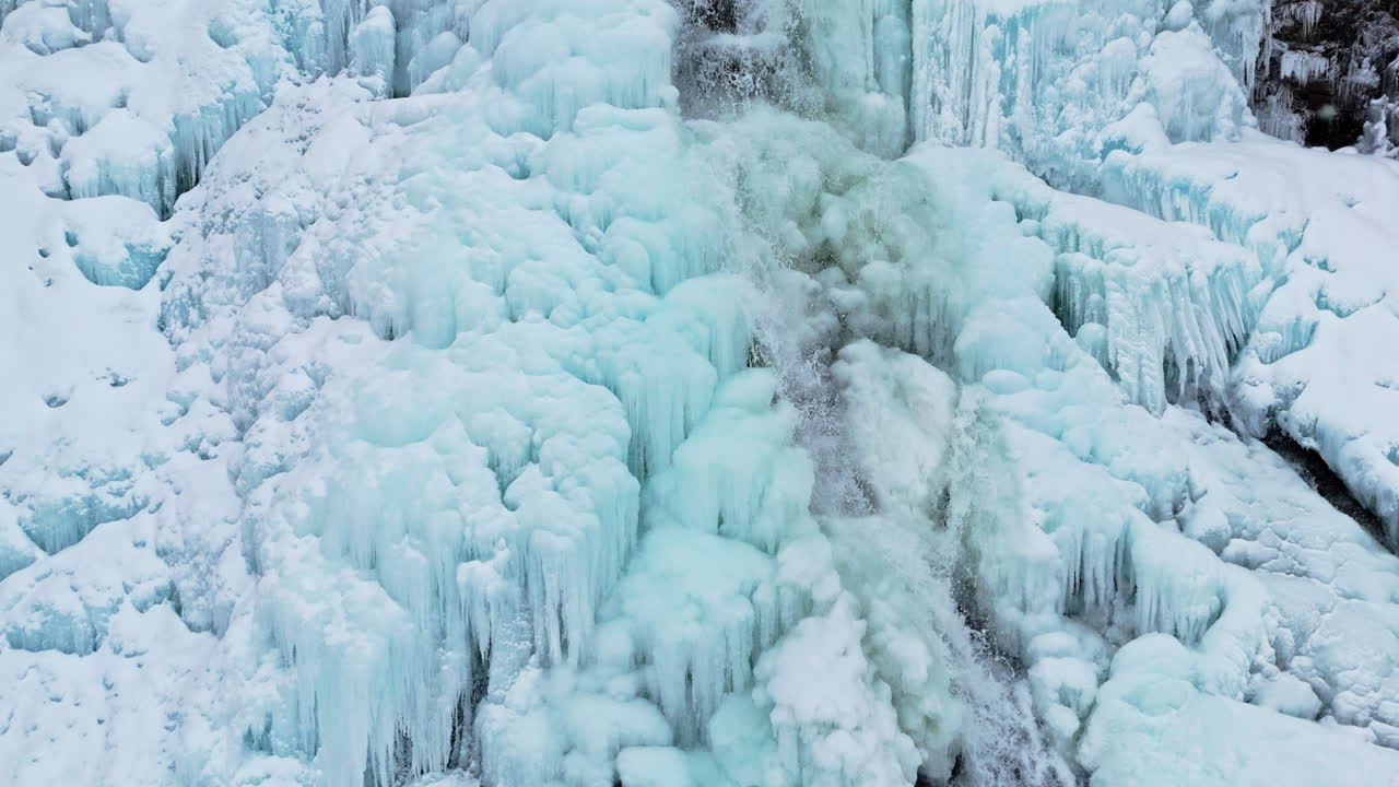 Frozen waterfall in Norway near Rovijoen Putous, icy blue formations and flowing water