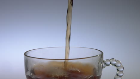 Close-up-of-tea-being-poured-into-a-clear-glass-in-slow-motion