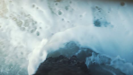 Vista-De-Arriba-Hacia-Abajo-De-Las-Olas-Rompiendo-Bajo-Un-Muelle,-Viejas-Bolas-De-Madera-En-Mal-Tiempo