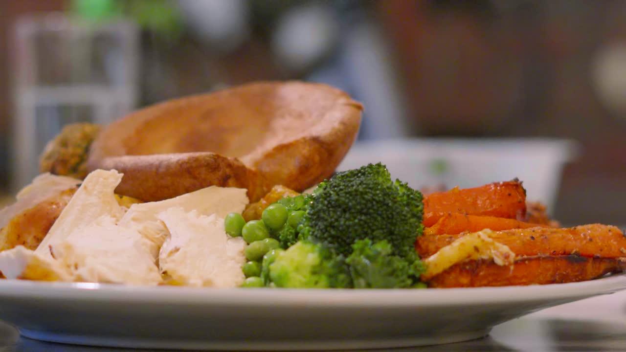 British Roast Chicken Dinner Plate with Vegetables and Yorkshire Pudding with Gravy Being Poured on in Slow Motion 4K.