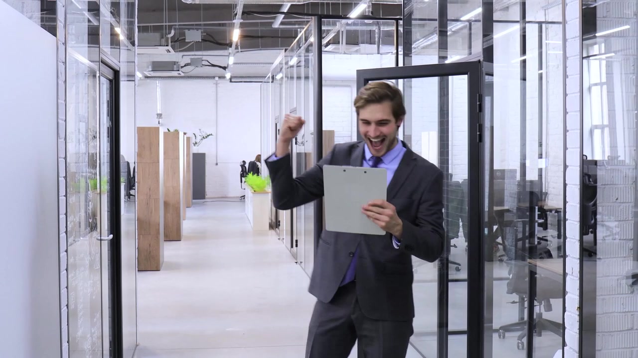 Empresario feliz caminando y celebrando el éxito en una oficina moderna