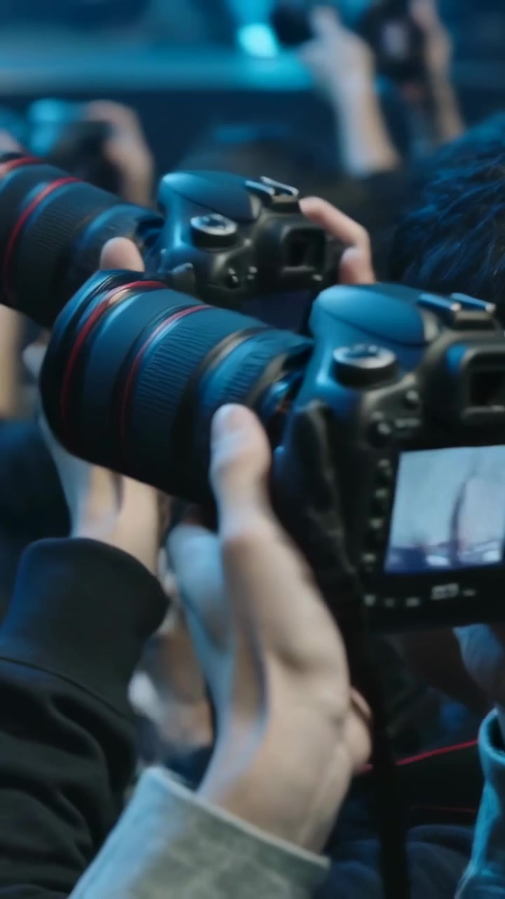 Video vertical: Hombre asiático en primer plano derecho operando una cámara DSLR, levantándola después de los pasos del artista, espacio para texto.