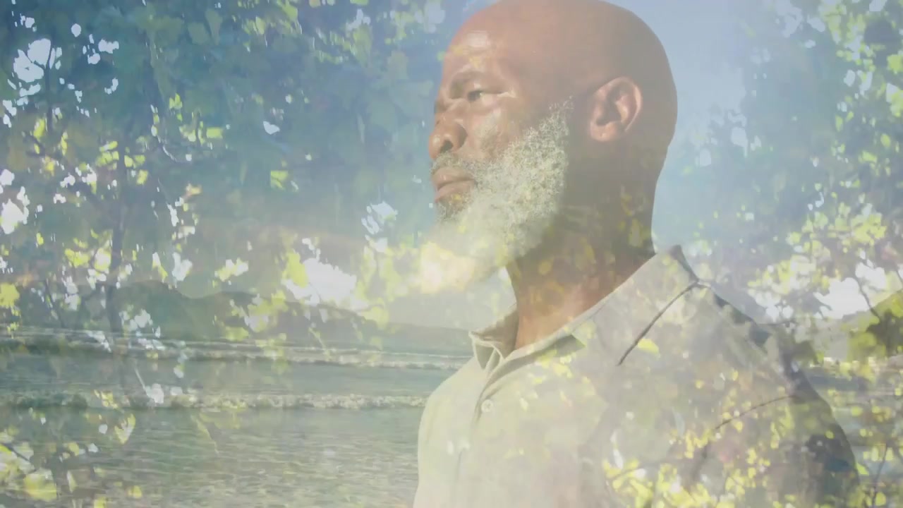 Camera moving revealing mature man holding gaze, overlaid leaves and ocean, for wellness branding