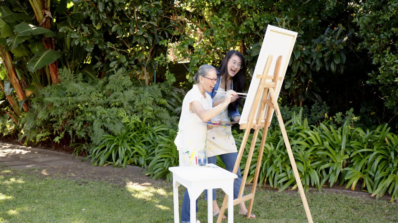 Painting on canvas, Asian grandmother and granddaughter enjoying outdoor art activity in garden