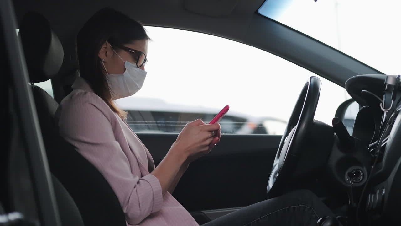 mujer conduciendo y usando teléfono móvil mientras lleva máscara